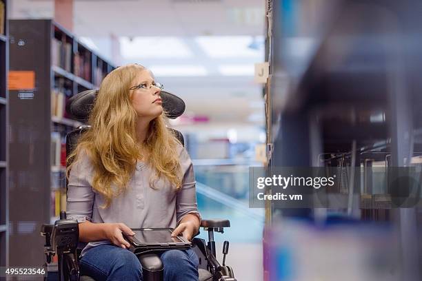 young woman in wealchair in library - choice student stockfoto's en -beelden