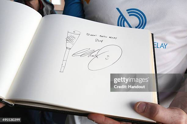 In this handout image provided by Glasgow 2014 Ltd, Baton bearer Iwan Thomas signs a book aboard Cunard's Queen Elizabeth ship as the Glasgow 2014...