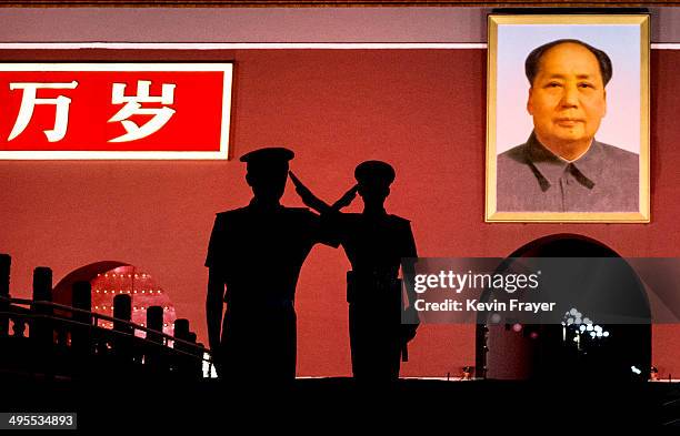 Chinese Paramilitary police officers salut each other as they stand guard below a portrait of the late leader Mao Zedong in Tiananmen Square on June...