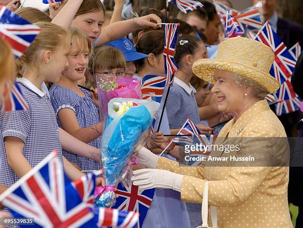 Queen Elizabeth II receives flowers from schoolgirls during the Queen's Golden Jubilee visit to West London on June 25, 2002 in Kingston upon Thames,...