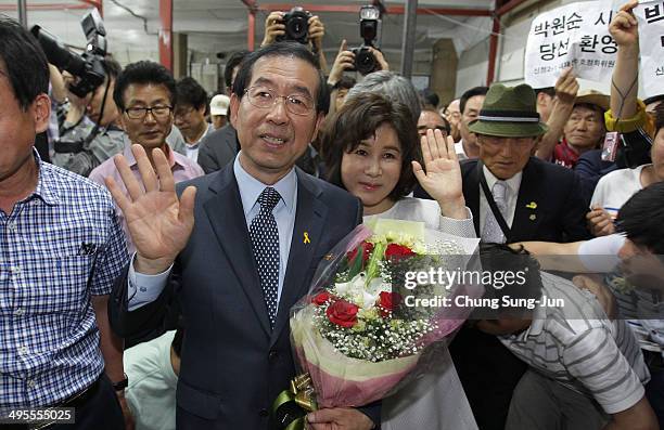 Seoul city mayor-elect Park Won-Soon of the main opposition party New Politics Alliance for Democracy celebrates holds flowers with his wife Kang...