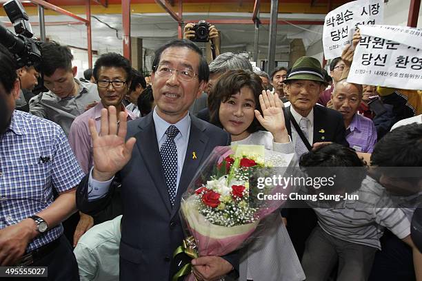 Seoul city mayor-elect Park Won-Soon of the main opposition party New Politics Alliance for Democracy celebrates holds flowers with his wife Kang...