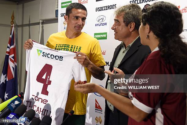 Australian Socceroos football player Tim Cahill is presented with a football shirt from local club Desportiva Ferroviaria at a press conference after...