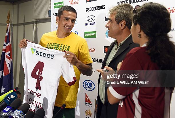 Australian Socceroos football player Tim Cahill is presented with a football shirt from local club Desportiva Ferroviaria at a press conference after...