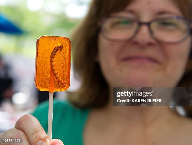 Patron shows a lollipop with an embedded mealworm June 4, 2014 during a global Pestaurant event sponsored by Ehrlich Pest Control, held at the...