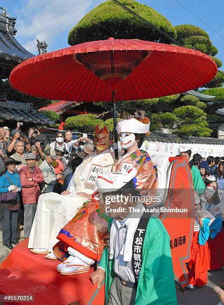 Rickshaw carrying a fox-masked couple posing as newlyweds moves past Hoshoji temple during the Inaho Festival on November 3, 2015 in Kudamatsu,...