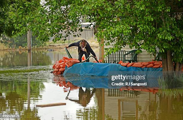 Farr West checks on his sump pump outside his home in Greeley that is flooded by rising water along the Poudre River, June 4, 2014. A flood warning...