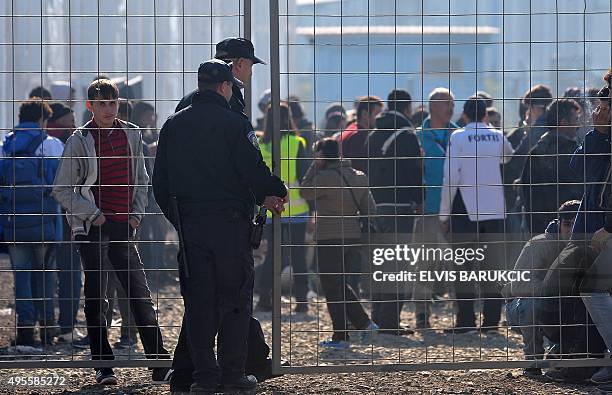 Croatian police stand guard as migrants and refugees queue to enter a transit camp in Slavonski Brod on November 4, 2015. Thousands of newly arrived...