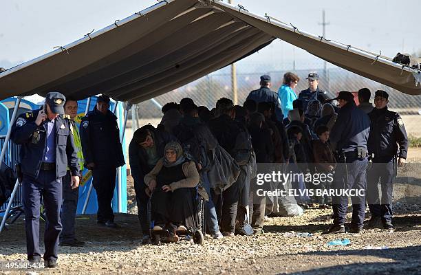 Croatian policemen stand guard as migrants and refugees queue to enter a transit camp in Slavonski Brod on November 4, 2015. Thousands of newly...