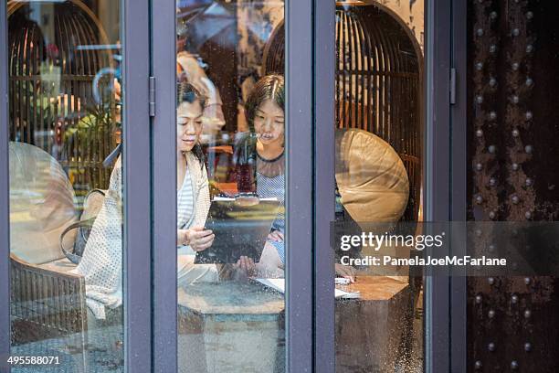 two asian women having a discussion in a restaurant - lech stock pictures, royalty-free photos & images