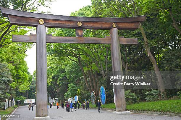 people walking under huge wood torii - meiji jingu shrine stock pictures, royalty-free photos & images