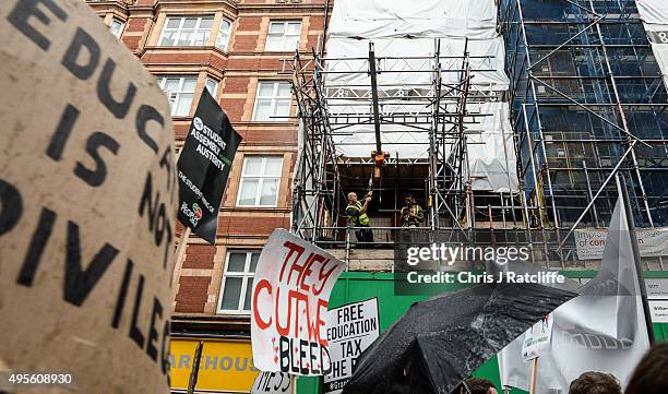 Workmen look on as students demonstrate against education cuts on November 4, 2015 in London, England. University students from across the country...