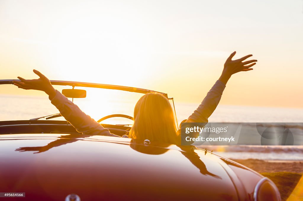 Frau beobachten den Sonnenuntergang in einem Cabrio Auto.