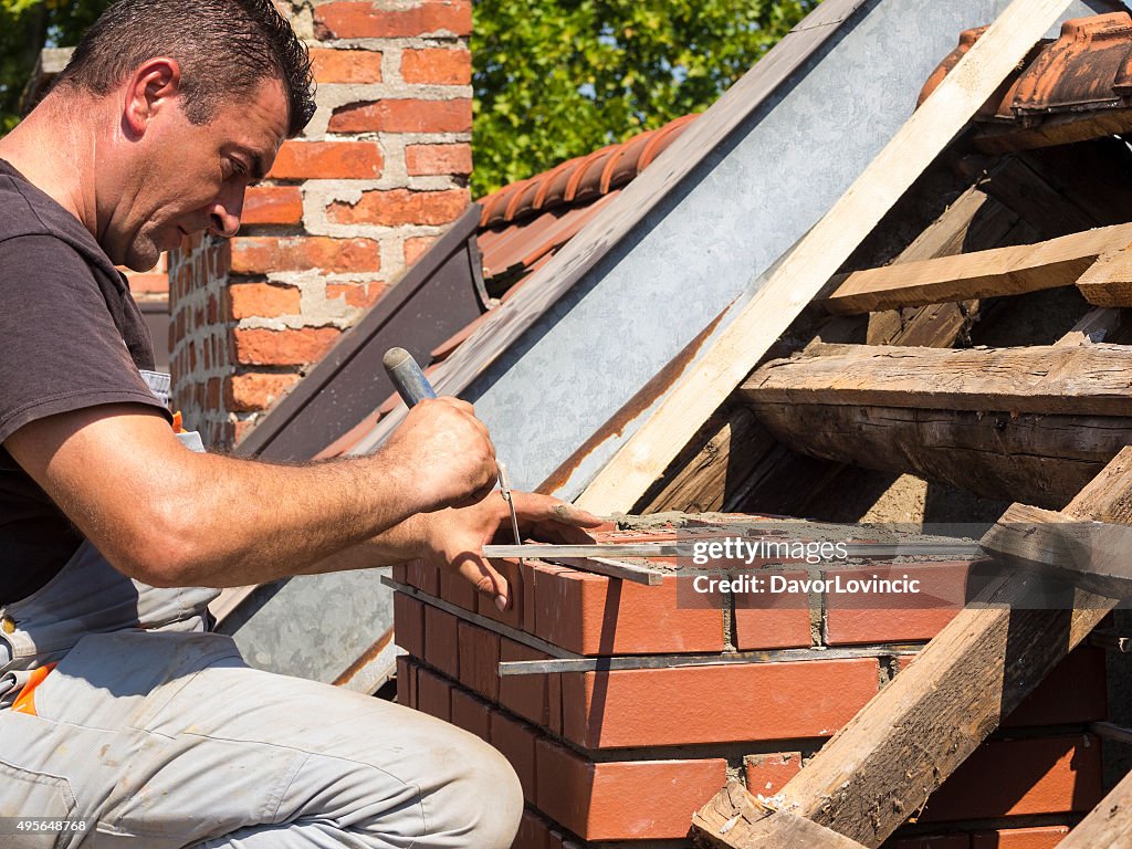 Working detail on brick chimney on an old roof