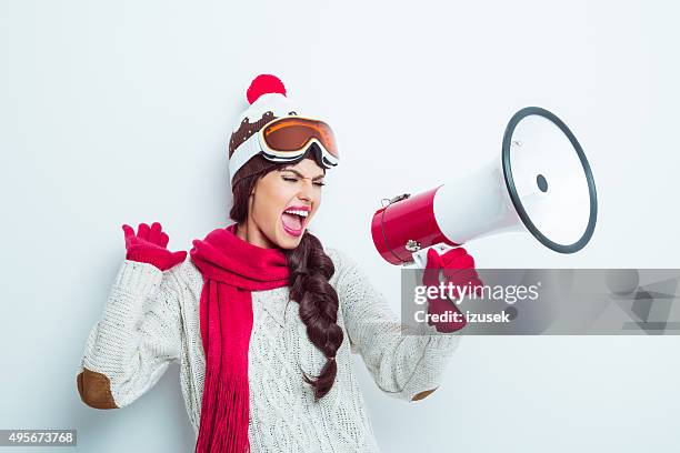 excited woman in winter outfit, shouting into megaphone - red glove stock pictures, royalty-free photos & images