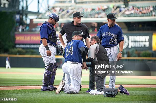 Jordan Lyles of the Colorado Rockies is looked after by Wilin Rosario, Walt Weiss, and Rockies trainer Keith Duggar after a play at home plate at...