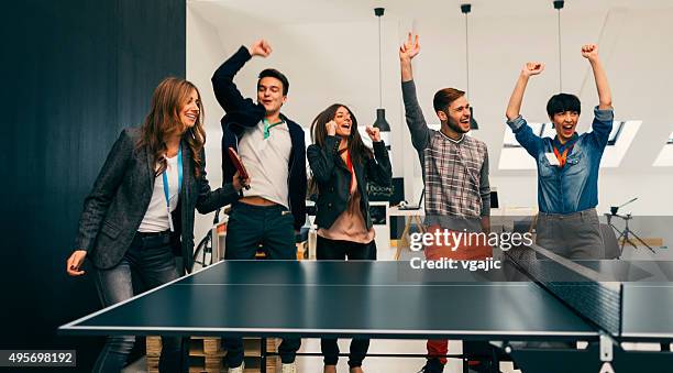 young business people playing table tennis in their office. - table tennis stock pictures, royalty-free photos & images