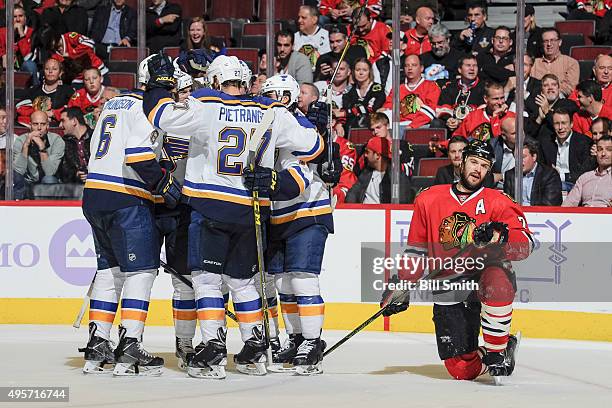 The St. Louis Blues celebrate after scoring and tying the game, as Brent Seabrook of the Chicago Blackhawks kneels to the side, in the second period...