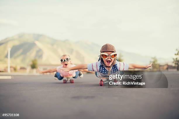 young boy and girl imagine flying on skateboard - european best pictures of the day january 15 2018 stockfoto's en -beelden