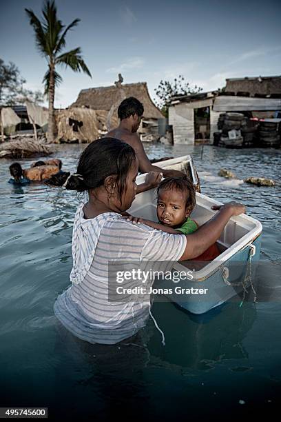 Little girl sitting in a floating cooler box after her village was flooded by the sea. The people of Kiribati are under pressure to relocate due to...