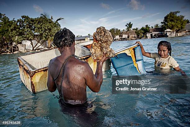 On the outskirts of the village Eita, family members gather rocks and corals from the seabed to build a stone wall as protection against rising sea...