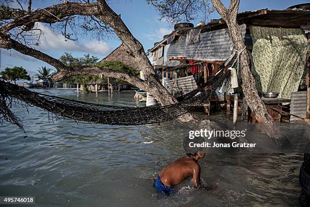 In the flooded village Eita, a young boy is swimming outside his house in the sea water. The people of Kiribati are under pressure to relocate due to...