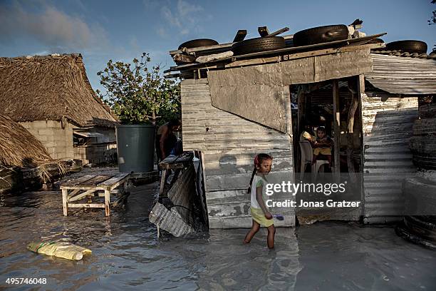 Young girl wades through the incoming sea water that flooded her house and village. The people of Kiribati are under pressure to relocate due to sea...