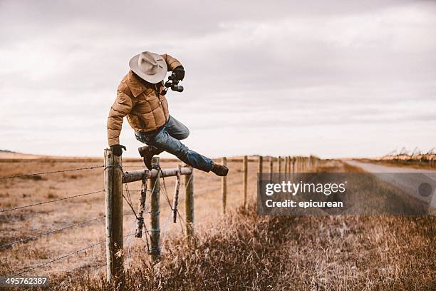 rancher jumps over stacheldraht zaun, um road - cow boy stock-fotos und bilder