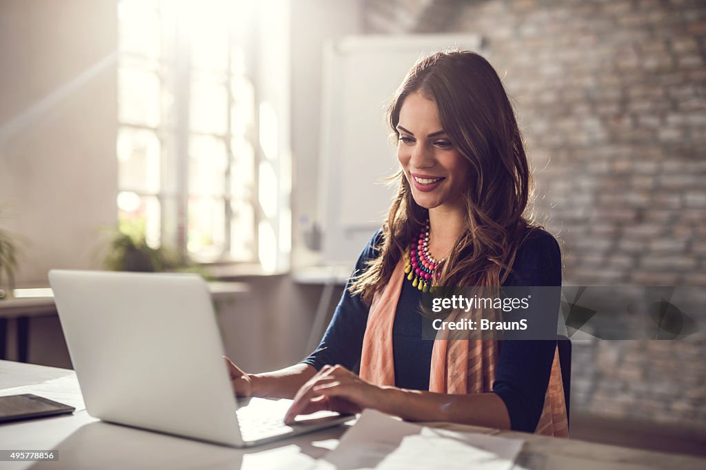 Heureux jeune femme d'affaires travaillant sur ordinateur portable dans le bureau.