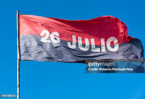 The July 26 Movement Flag flying against clear blue sky. Cuban flag with 26 Julio written on it. The July 26 Movement was a revolutionary...