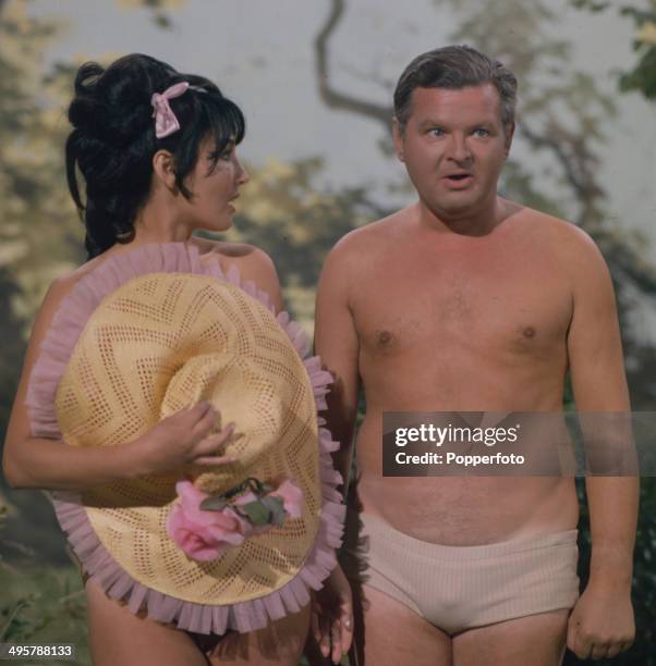 English comedian and actor Benny Hill in his underwear with Belgian actress Bettina Le Beau in a scene from his television series 'The Benny Hill...