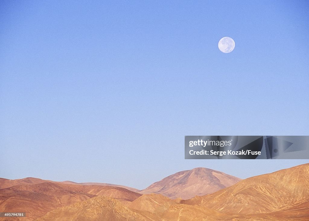 Desert wilderness landscape with full moon low on horizon, Tibet, China