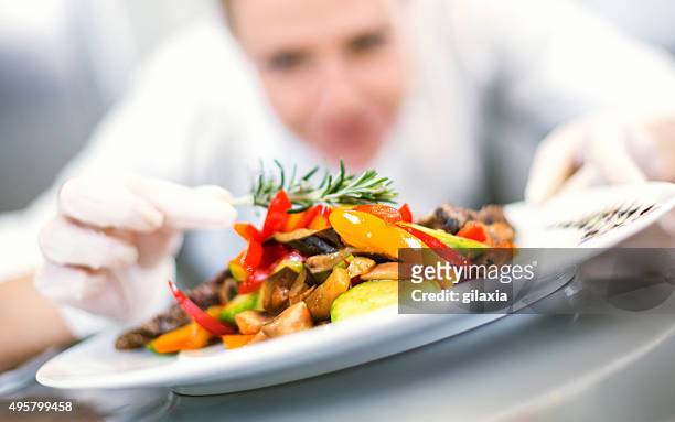 female chef places finishing touches on meal. - serveringsklar bildbanksfoton och bilder