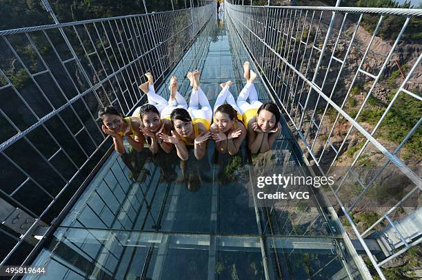 Yoga enthusiasts practice on a glass suspension bridge at the Shiniuzhai National Geological Park on November 5, 2015 in Pingjiang County, Yueyang...