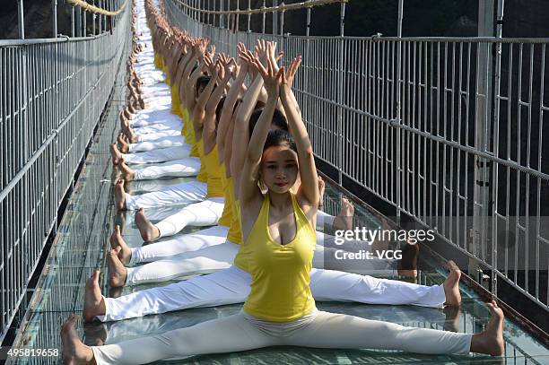 Yoga enthusiasts practice on a glass suspension bridge at the Shiniuzhai National Geological Park on November 5, 2015 in Pingjiang County, Yueyang...