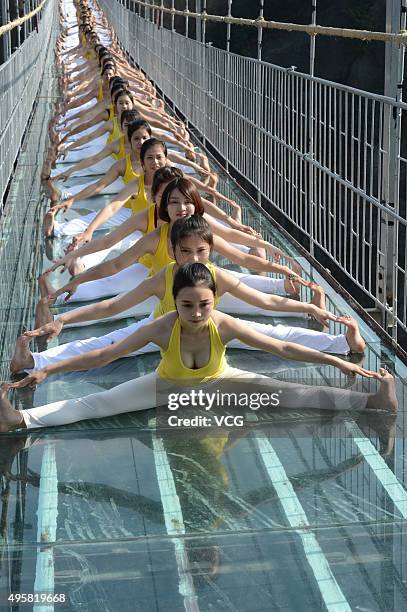 Yoga enthusiasts practice on a glass suspension bridge at the Shiniuzhai National Geological Park on November 5, 2015 in Pingjiang County, Yueyang...