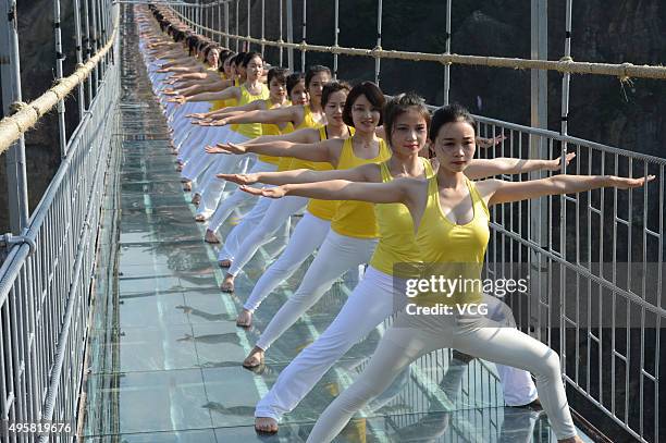 Yoga enthusiasts practice on a glass suspension bridge at the Shiniuzhai National Geological Park on November 5, 2015 in Pingjiang County, Yueyang...