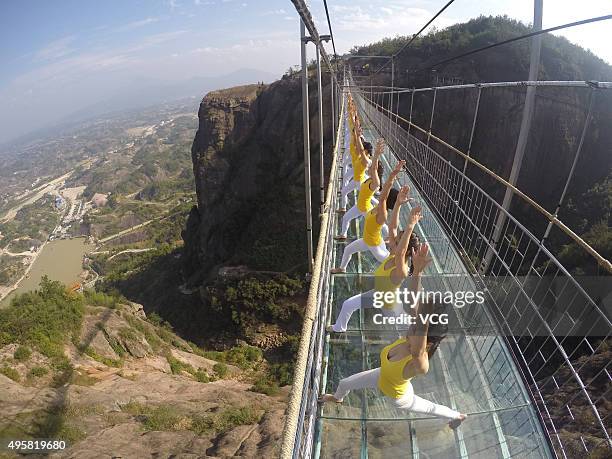 Yoga enthusiasts practice on a glass suspension bridge at the Shiniuzhai National Geological Park on November 5, 2015 in Pingjiang County, Yueyang...