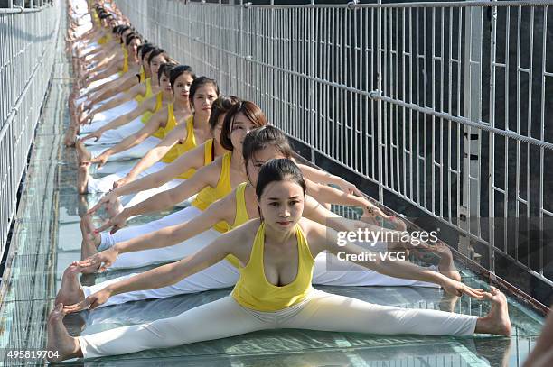 Yoga enthusiasts practice on a glass suspension bridge at the Shiniuzhai National Geological Park on November 5, 2015 in Pingjiang County, Yueyang...