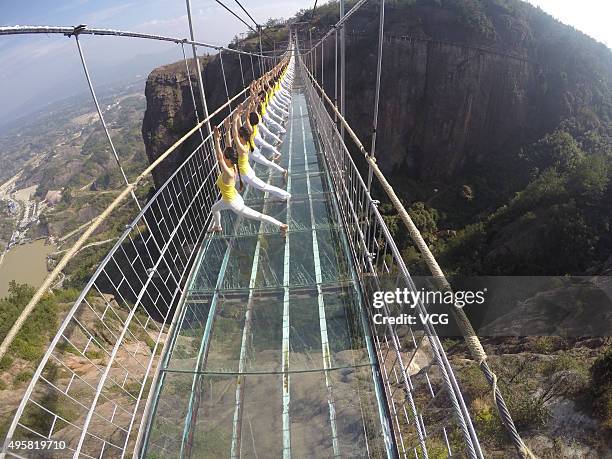 Yoga enthusiasts practice on a glass suspension bridge at the Shiniuzhai National Geological Park on November 5, 2015 in Pingjiang County, Yueyang...