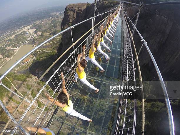 Yoga enthusiasts practice on a glass suspension bridge at the Shiniuzhai National Geological Park on November 5, 2015 in Pingjiang County, Yueyang...