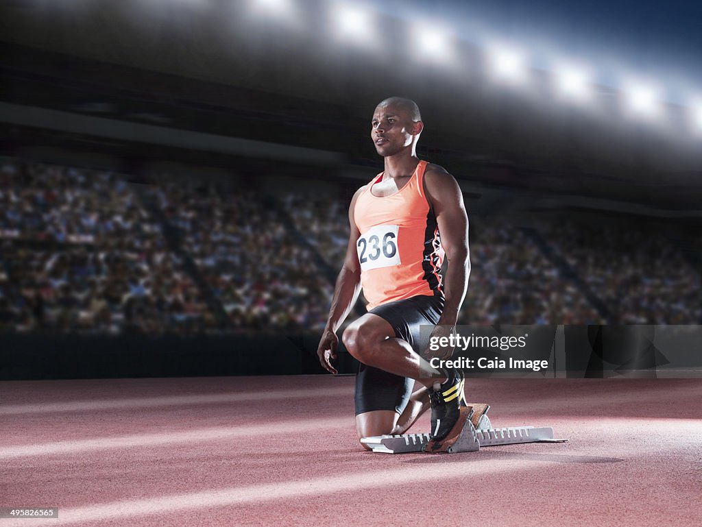 Runner with feet in starting block on track