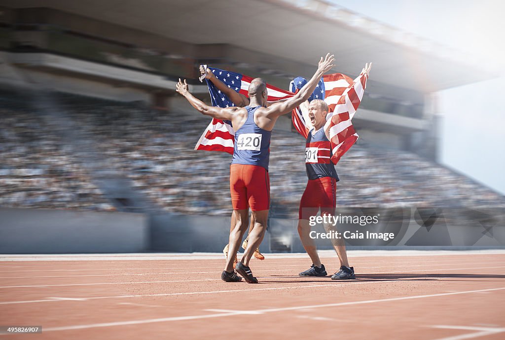 Runners celebrating and holding American flags on track