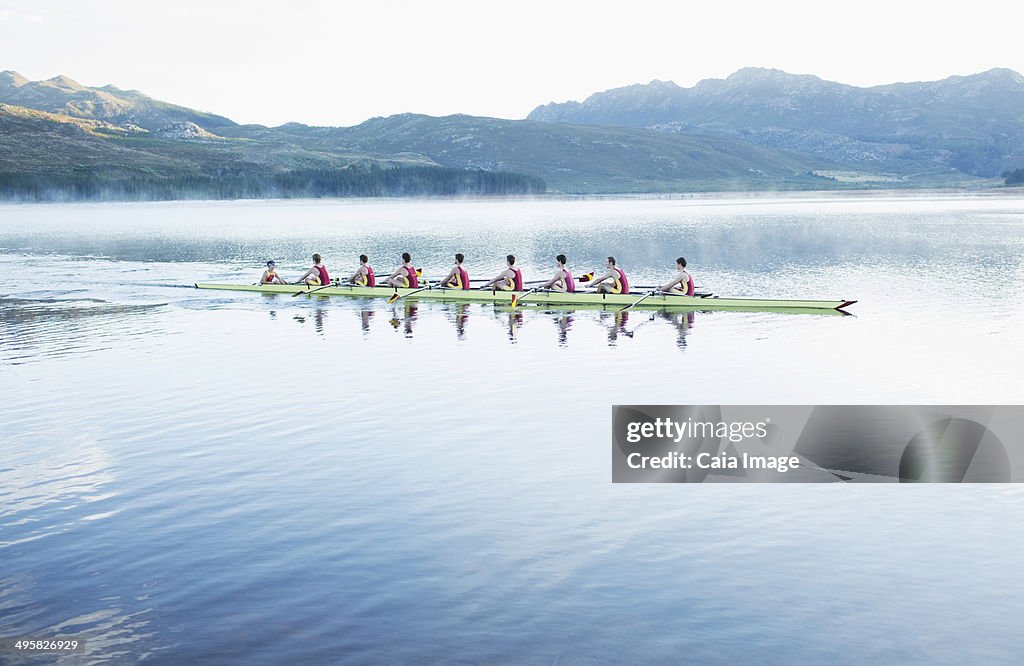 Rowing team rowing scull on lake