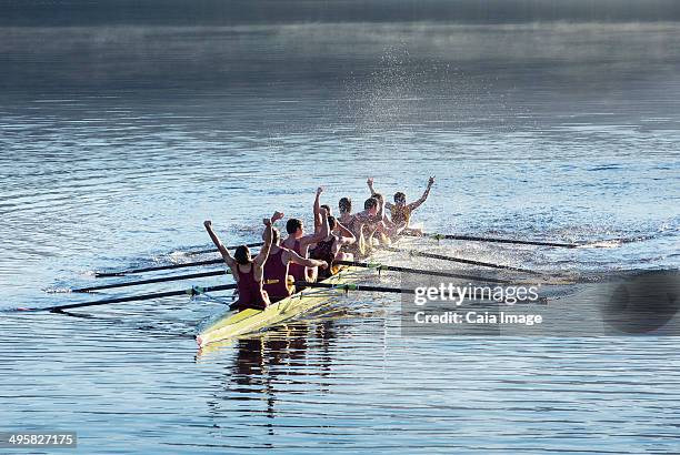 rowing team celebrating in scull on lake - mondo beat foto e immagini stock