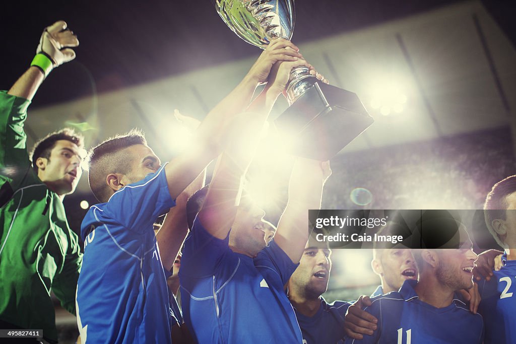 Soccer team celebrating with trophy on field