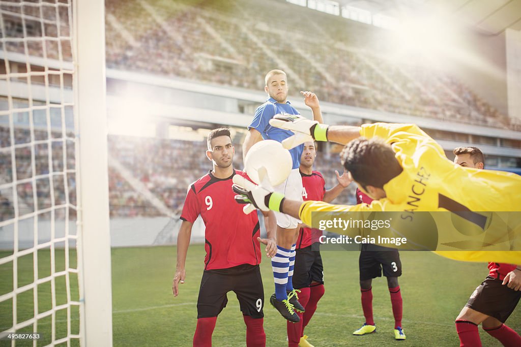 Goalie jumping for ball in soccer net