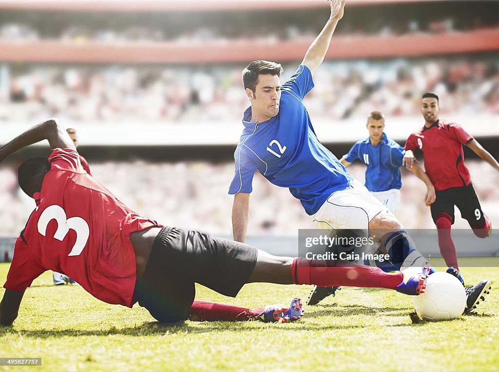 Soccer players kicking ball on field