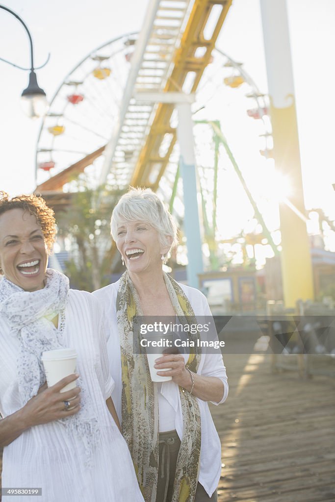 Senior women laughing and drinking coffee at amusement park