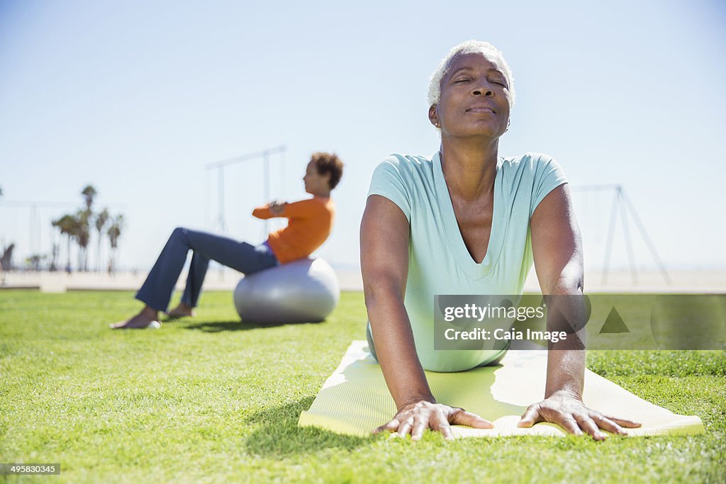 Women practicing yoga in sunny park